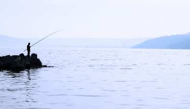 man on small island fishing