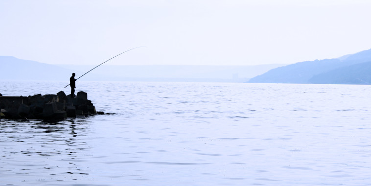 man on small island fishing