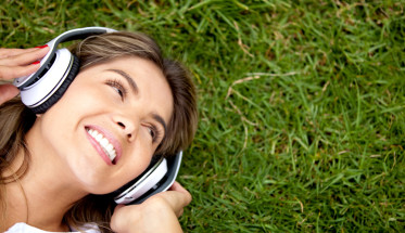 girl laying in grass with headphones